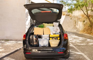 Kutuları ve bavulları taşımak, çeşitli eşyalar, caddenin yanındaki siyah arabanın açık bagajındaki bitkiler, insanlar olmadan, kopyalama alanı. Taşınma, taşınma, emlak, yeni başlangıç konsepti