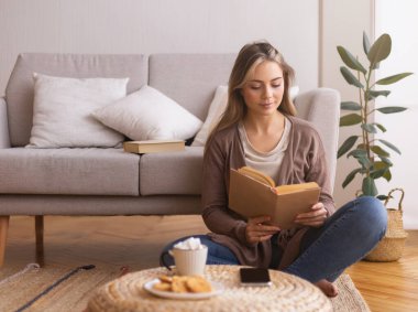 Tembel hafta sonu. Kitap okuyan tatlı bir kız, evde yerde oturuyor, boş bir yer.