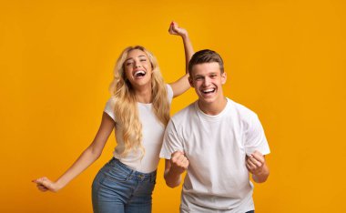 - Başardık. Başarılı sınavları kutlayan öforik genç öğrenciler, sarı stüdyo arka planı ve boş alan.