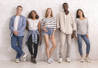 Beyaz duvar üzerinde poz veren bir grup uluslararası öğrenci, gençlik kültürü kavramı.