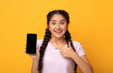 İnanılmaz Faydalı Uygulama. Heyecanlı genç Hintli kadının portresi elinde siyah ekranı olan akıllı telefonu tutuyor, cihaza işaret ediyor, şablon oluşturmak için boş alanı olan cihazları gösteriyor.