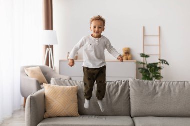 Neşeli Afrika kökenli Amerikalı küçük çocuk evde kameraya gülümseyen orta-havada eğlenceli pozlar veriyor. Kaygısız Çocuk içeride vakit geçiriyor. Çocukluk Eğlencesi, Mutluluk Konsepti