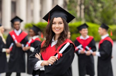 Mezuniyet partisi veren, mezuniyet kostümü giyen, elinde diploma tutan, üniversite kampüsünde gururla poz veren, geçmişi bulanık genç bir kız öğrenci.