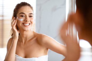 Gülümseyen Kadın Göz Altında Yüz Kremi Uyduruyor Nemlendirici Cilt Pozu Yakınındaki Modern Tuvalette Duruyor. Güzellik rutini, yüz derisi konsepti. Seçici Odaklanma