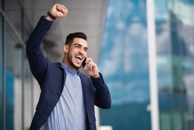 Mest olmuş Arap iş adamı iş ortağıyla telefonda konuşuyor, elini kaldırıyor, başarıyı kutluyor. Orta Doğulu girişimci asistanıyla akıllı telefondan konuşuyor, iyi haberler var.