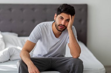Genç Arap adam sabah uyanıp yatakta oturduktan sonra baş ağrısı ya da migrenden muzdarip. Yüzünde acı ifadesi olan, akşamdan kalma, stresli bir adam.