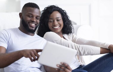 Komik videolar izlerken ve gülerek, closeup dijital tablet kullanarak Neşeli Afrikalı Amerikalı çift