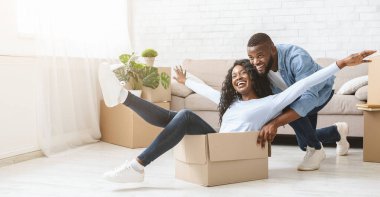 Genç Afrikalı adam içinde onun kadın ile ambalaj kutusu iterek, yeni bir evde hareket ederken eğlenmek, kopya alanı ile panorama
