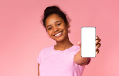 Sevimli afro-amerikan kız boş akıllı telefon ekranı gösteren, eğitim uygulaması veya web sitesi için mükemmel. Boş alana sahip pembe arka plan.