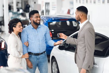 Araba kiralama konsepti. Otomobil Kiralama Ofisinde Bekleyen Yöneticiden Otomobil Anahtarı Alan Afro Çift.