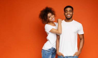 Turuncu stüdyo arka planda sevimli güzel Afrikalı-Amerikalı adam ve kadın kucaklama, kopya alanı