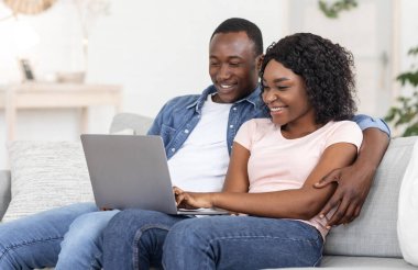 Neşeli siyah adam ve kadın dizüstü bilgisayardan, iç mekandan, kopyalama alanından fotoğraflar izliyor.