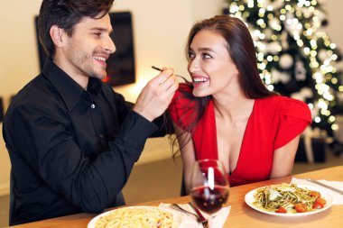 Valentines Date. Cheerful Beautiful Elegant Couple Feeding Each Other Having Romantic Dinner In Restaurant Or At Home Eating Gourmet Delicious Italian Pasta Spending Time Together Celebrating Holiday