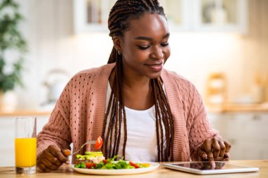 Genç Afrikalı Amerikalı Kadın Kicthen 'da Kahvaltı Yapıyor ve Dijital Tablet Kullanıyor, Siyahi Kadın İnternet' te Yeni Uygulamalara Bakıyor veya İnternetten Alışveriş Yapıyor