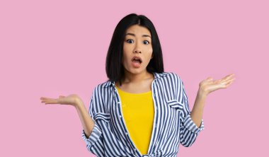 Kim bilir. Omuzlarını silkeleyen komik Asyalı kadının portresi Pembe Arkaplan 'da kamera pozuna bakıyor. Stüdyo çekimi. Kafası karışık bayan hiçbir şey bilmiyor. Özür dilerim, izninizle. Karar veremiyorum.