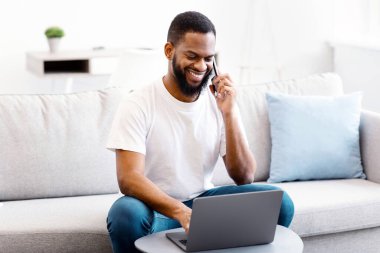 Cep telefonuyla konuşan Afro-Amerikalı adam evde koltukta oturuyor. Her zaman temas halinde, serbest yaşam tarzı, ve uzak mobil iletişim. Seçici Odaklanma