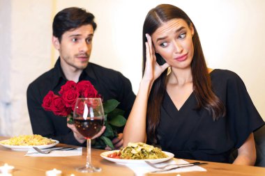 Bad Date. Young Couple Having Unsuccessful Meeting In Restaurant, Funny Disappointed Shoked Woman Feeling Embarrassment Covering Face, Man Giving Her Bouquet Of Red Roses