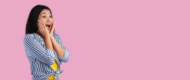 Harika bir öneri. Şaşırmış Asyalı genç bir kadının portresi ücretsiz fotokopi alanına bakıyor. Ağzı açık ve inançsız bir şekilde yüzlerine dokunuyor. Pembe stüdyo arka planında izole edilmiş.