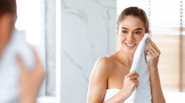 Yüz bakımı, hijyen. Modern banyoda yıkandıktan sonra havluyla yüzünü kurutan çekici bayan. Sabah Güzelliği Rutini Konsepti. Seçici Odaklanma, Panorama