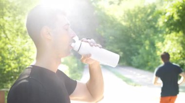 Genç bir adam yaz boyunca yemyeşil bir parkta koşarken susuz kalır. Atletik biçimi, sağlıklı bir yaşam tarzı ve formda kalma alışkanlığını yansıtıyor..