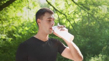 Genç bir adam dışarı çıktıktan sonra bir içkiyle su içmek için ara verir. Bereketli yeşilliklerle çevrili halde, sıcacık yaz gününün tadını çıkarırken spor rutinini sürdürüyor..