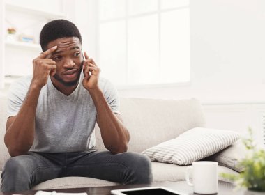 Üzgün, Afro-Amerikalı bir adam akıllı telefondan konuşuyor. Duygusal bir şekilde evdeki bej koltukta oturuyor ve uzayı kopyalıyor.