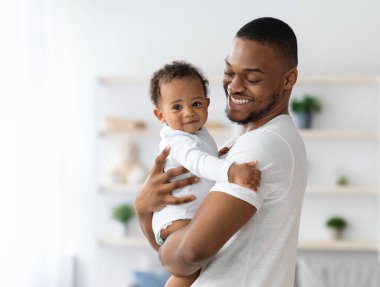 Mutlu Afrika kökenli Amerikalı baba, sevimli yeni doğmuş bebeğini kucaklıyor, siyah babayı seviyor, tatlı bebekle vakit geçiriyor, ona sarılıyor, babalık izninin tadını çıkarıyor, boşluğu kopyalıyor.