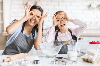 Sevimli küçük kız ve onun güzel annesi oynuyor ve evde mutfakta pişirme sırasında gülümsüyor, freespace