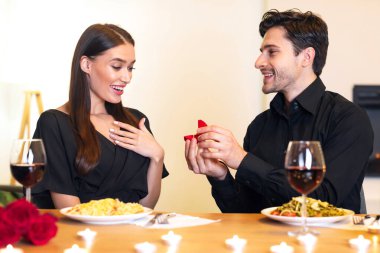 Benimle evlenir misin? Yakışıklı sakallı adam, kutuyu tutuyor ve gösteriyor. Şaşırmış nişanlısına evlilik yüzüğü veriyor. Romantik bir randevu sırasında restoranda veya evde nişanlanıyor. Karım Ol