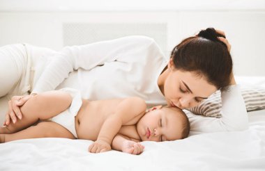 Sıcak anne seviyorum. Genç Anne yatakta uyuyan onun yeni doğan bebek öpüşme.