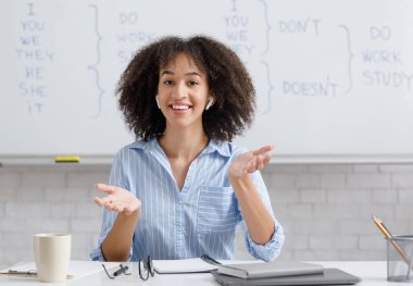 Modern teknoloji, sağlık koronavirüsten korur ve uzaktan evden çalışır. Kablosuz kulaklıklı neşeli Afro-Amerikan kadın oturma odasında İngilizce kurallarını anlatıyor.