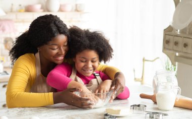 Mutfakta Mutlu Aile. Siyah Anne ve Küçük Kızı Birlikte Hamur Hazırlıyor, Afrikalı Amerikalı Anne 'yi seviyor, çocuğuna yemek pişiriyor, ev yapımı hamur işleri pişiriyor,