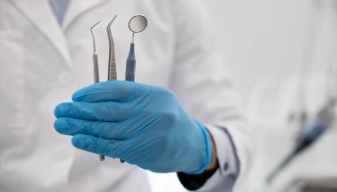 Tanınmayan Diş Hekimi Mavi Steril Eldiven Tutan Diş Hekimi Ağız Aynası, İnceleme ve Paslanmaz Cımbız Kaliteli Stomatolojik Hizmetler İçin Yaratıcı Sancak