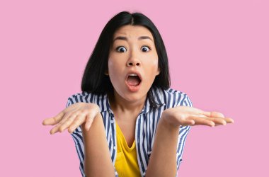 Vay canına Omg. Şaşırmış genç Asyalı kadının yakından çekilmiş portresi ağzı açık kameraya bakıyor, el kol hareketi yapıyor, haber ya da teklif karşısında şoka uğruyor, pembe stüdyo arka planında tek başına duruyor.