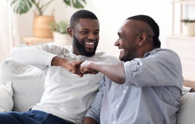 Baba-oğul dostluğu. Siyahi Milenyum Adamı, büyük babasıyla evde yumruk tokuşturuyor, birlikte vakit geçirmenin keyfini çıkarıyor, yakın plan yapıyor.