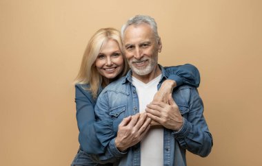 Sevgi dolu, güzel, son sınıf güzeli çift, gri saçlı yakışıklı adam ve sarışın güzel bayanın renkli pastel stüdyo arka planında birbirlerine bağlanıp kameraya gülümsemelerinin portresi. Aşk, sevgi, evlilik.