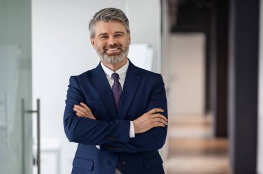 Yakışıklı, orta yaşlı, takım elbiseli bir işadamının portresi, başarılı bir erkek girişimci pozisyonu ofis salonunda, profesyonel hizmetler reklamcılığı, kamera karşısında gülümseme.