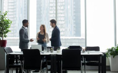 Kahve molası. İş adamları toplantının ardından ofis penceresinin önünde konuşuyorlar, masanın yanında duruyorlar, boş alanlar.