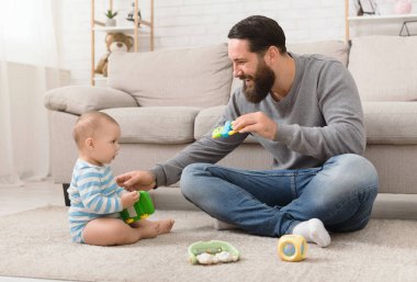 Oyun zamanı. Millennial baba tatlı bir çocukla oyun oynuyor, yerde birlikte oynuyorlar.