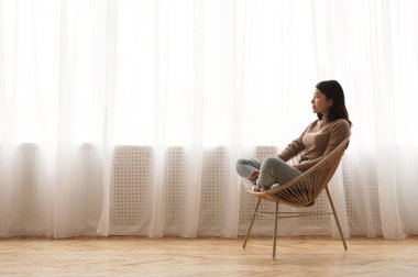 Sabah uyumu. Hasır sandalyede dinlenen ve hayal kuran kız pencereye, yan görüntüye, boşluğu kopyala