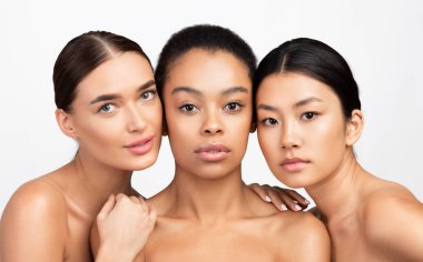 Beauty. Portrait Of Three Mixed Girls Looking At Camera Posing Naked Over White Background. Studio Shot