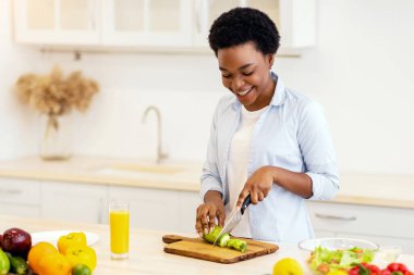 Akşam yemeği için salata pişiren siyah kadın modern mutfakta duran sebzeleri kesiyor. Sağlıklı yiyecekler, yiyecekler, beslenme, diyet ve kilo verme reçeteleri. Seçici Odaklanma
