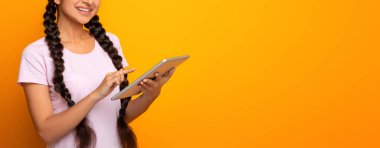 İnsanlar, Teknoloji ve İletişim. Elinde dijital tablet olan gülümseyen Hintli genç bir kadının portresi sarı stüdyo arka planında izole bir şekilde duruyordu. Neşeli kadın modern cihaz, bayrak kullanıyor