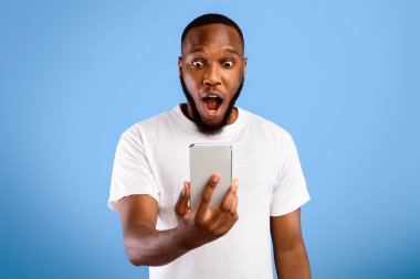 Vay canına. Şok oldum. Elinde telefon tutan siyahi adam, sürpriz mesaj okuyor. Mavi Stüdyo 'nun arka planında ağzı açık bir şekilde poz veriyor. Akıllı Telefon Konsepti için Yeni Mobil Uygulama
