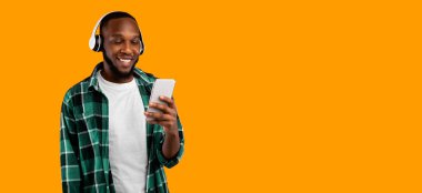 Müzik uygulaması. Kulaklık takan siyahi adam Sarı Stüdyo Arkaplanı Üzerinde Duran Harika Şarkı 'yı dinliyor. Metin için Boş Alanı Olan Panorama