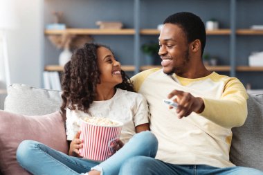 Sevimli siyah aile babası ve kızı evde birlikte televizyon izliyorlar. Gülümseyen Afrikalı Amerikalı baba ve liseli kız komik çizgi film izleyip patlamış mısır yiyor, kanepede oturuyor ve uzayı kopyalıyor.