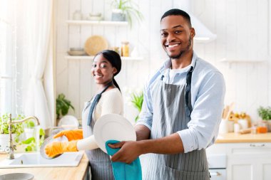 Mutfakta bulaşık yıkayan mutlu siyah çift, fotokopi odası. Genç Afro-Amerikalı bir adam, karısı evde temizlerken tabakları siliyor. Aile işleri konsepti