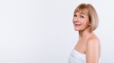 Doğal güzellik. Havlulu yaşlı bir kadının profil portresi pürüzsüz ipek tenli, açık mavi stüdyo arka planında poz veren, fotokopi alanı olan afiş tasarımı. Sağlık ve cilt bakımı kavramı