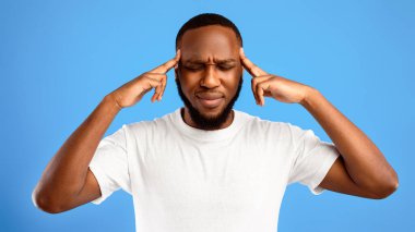 Beyin işi. Mavi Stüdyo 'nun arka planında duran ve gözleri kapalı bir şekilde masaj yapan düşünceli Afrikalı Amerikalı adam. Dalgın Siyah Adam 'ın Portresi. Panorama