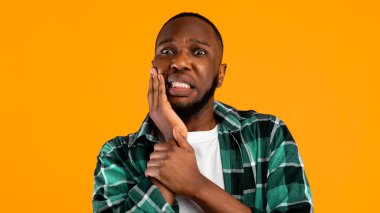 Diş ağrısı. Sarı Stüdyo 'nun arka planında dikilip kameraya bakarken Diş Ağrısı Pozu Çeken Yanak Dokunan Korkak Zenci Adam. Ağrıyan Diş Problemi Konsepti. Panorama
